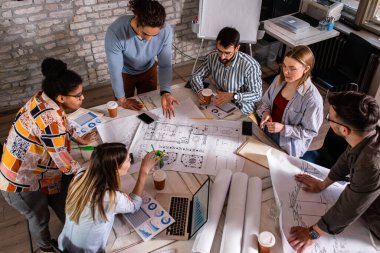 Modern iş adamlarından oluşan bir grup, yaratıcı ofiste mimari tasarımları tartışıyor..