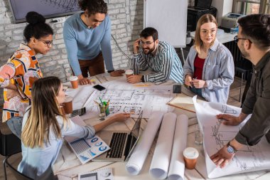 Modern iş adamlarından oluşan bir grup, yaratıcı ofiste mimari tasarımları tartışıyor..