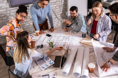 Modern iş adamlarından oluşan bir grup, yaratıcı ofiste mimari tasarımları tartışıyor..