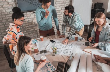 Modern iş adamlarından oluşan bir grup, yaratıcı ofiste mimari tasarımları tartışıyor..