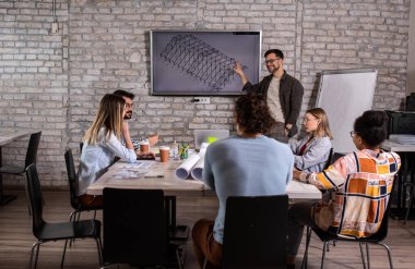 Modern iş adamlarından oluşan bir grup, yaratıcı ofiste mimari tasarımları tartışıyor..
