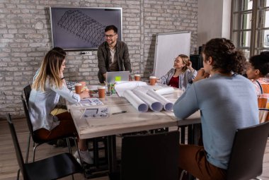 Modern iş adamlarından oluşan bir grup, yaratıcı ofiste mimari tasarımları tartışıyor..