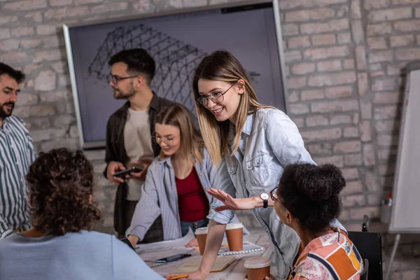 Modern iş adamlarından oluşan bir grup, yaratıcı ofiste mimari tasarımları tartışıyor..