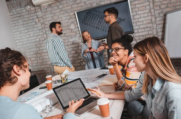 Modern iş adamlarından oluşan bir grup, yaratıcı ofiste mimari tasarımları tartışıyor..