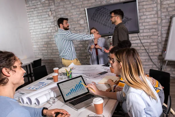 Modern iş adamlarından oluşan bir grup, yaratıcı ofiste mimari tasarımları tartışıyor..