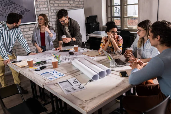 Modern iş adamlarından oluşan bir grup, yaratıcı ofiste mimari tasarımları tartışıyor..