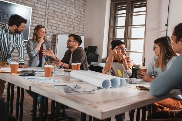 Modern iş adamlarından oluşan bir grup, yaratıcı ofiste mimari tasarımları tartışıyor..