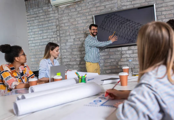 Modern iş adamlarından oluşan bir grup, yaratıcı ofiste mimari tasarımları tartışıyor..