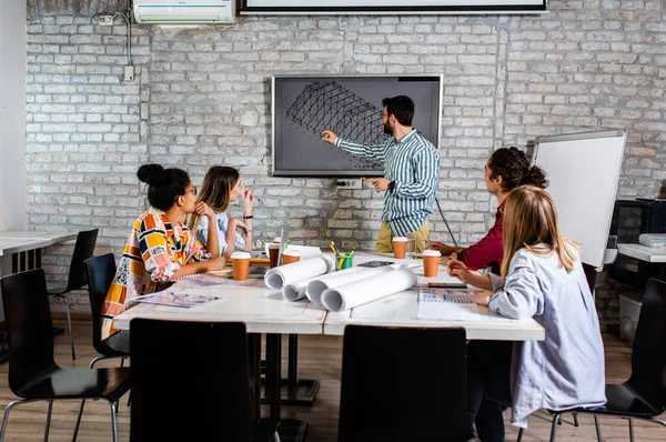 Modern iş adamlarından oluşan bir grup, yaratıcı ofiste mimari tasarımları tartışıyor..