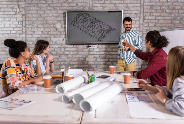Modern iş adamlarından oluşan bir grup, yaratıcı ofiste mimari tasarımları tartışıyor..