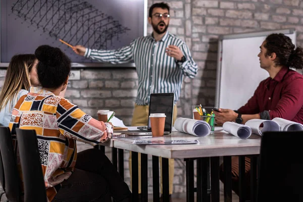 Modern iş adamlarından oluşan bir grup, yaratıcı ofiste mimari tasarımları tartışıyor..