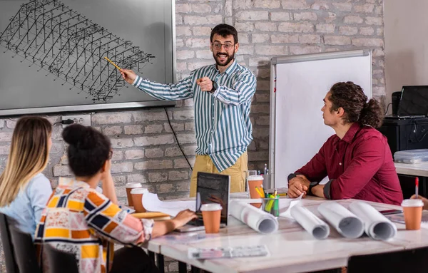 Modern iş adamlarından oluşan bir grup, yaratıcı ofiste mimari tasarımları tartışıyor..