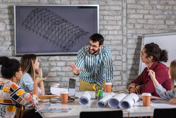 Modern iş adamlarından oluşan bir grup, yaratıcı ofiste mimari tasarımları tartışıyor..