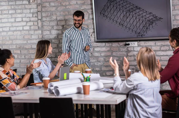 Modern iş adamlarından oluşan bir grup, yaratıcı ofiste mimari tasarımları tartışıyor..
