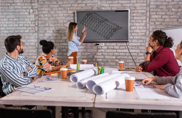 Modern iş adamlarından oluşan bir grup, yaratıcı ofiste mimari tasarımları tartışıyor..