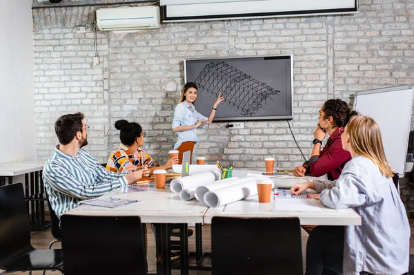 Modern iş adamlarından oluşan bir grup, yaratıcı ofiste mimari tasarımları tartışıyor..