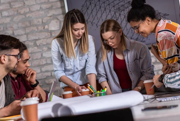 Modern iş adamlarından oluşan bir grup, yaratıcı ofiste mimari tasarımları tartışıyor..