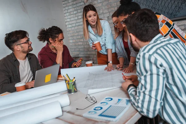 Modern iş adamlarından oluşan bir grup, yaratıcı ofiste mimari tasarımları tartışıyor..