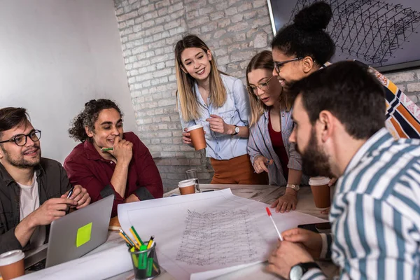 Modern iş adamlarından oluşan bir grup, yaratıcı ofiste mimari tasarımları tartışıyor..