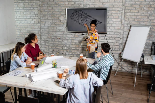 Modern iş adamlarından oluşan bir grup, yaratıcı ofiste mimari tasarımları tartışıyor..