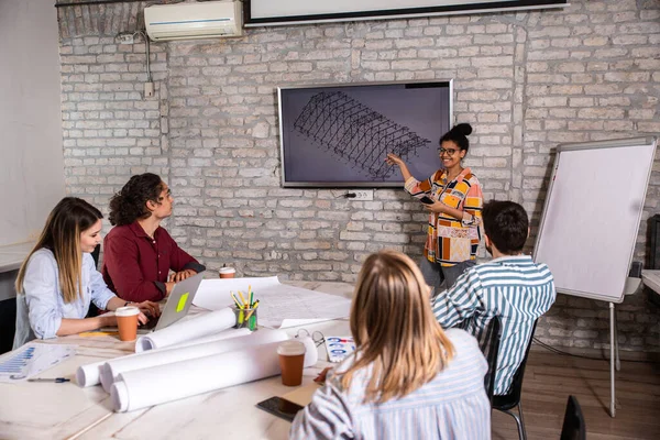 Modern iş adamlarından oluşan bir grup, yaratıcı ofiste mimari tasarımları tartışıyor..