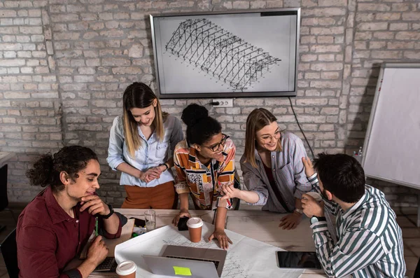 Modern iş adamlarından oluşan bir grup, yaratıcı ofiste mimari tasarımları tartışıyor..