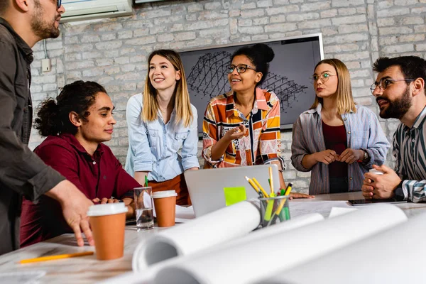 Modern iş adamlarından oluşan bir grup, yaratıcı ofiste mimari tasarımları tartışıyor..