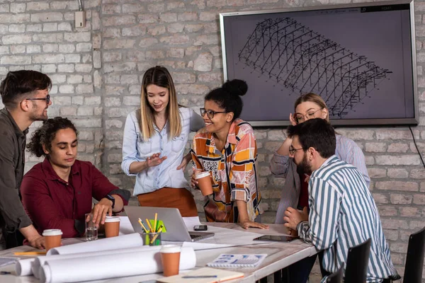 Modern iş adamlarından oluşan bir grup, yaratıcı ofiste mimari tasarımları tartışıyor..