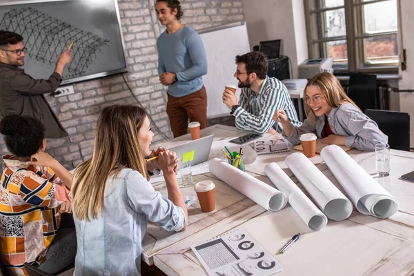 Modern iş adamlarından oluşan bir grup, yaratıcı ofiste mimari tasarımları tartışıyor..