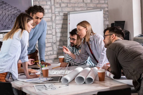 Modern iş adamlarından oluşan bir grup, yaratıcı ofiste mimari tasarımları tartışıyor..