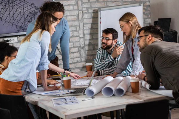 Modern iş adamlarından oluşan bir grup, yaratıcı ofiste mimari tasarımları tartışıyor..