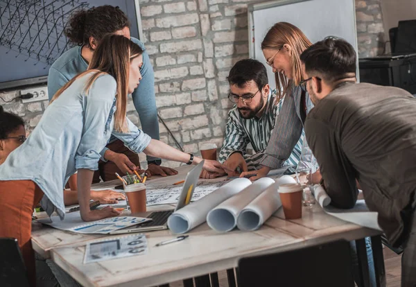 Modern iş adamlarından oluşan bir grup, yaratıcı ofiste mimari tasarımları tartışıyor..