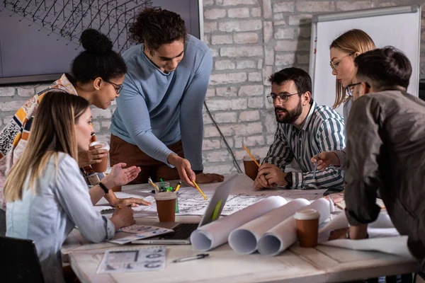 Modern iş adamlarından oluşan bir grup, yaratıcı ofiste mimari tasarımları tartışıyor..
