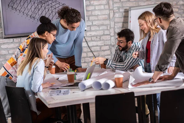 Modern iş adamlarından oluşan bir grup, yaratıcı ofiste mimari tasarımları tartışıyor..