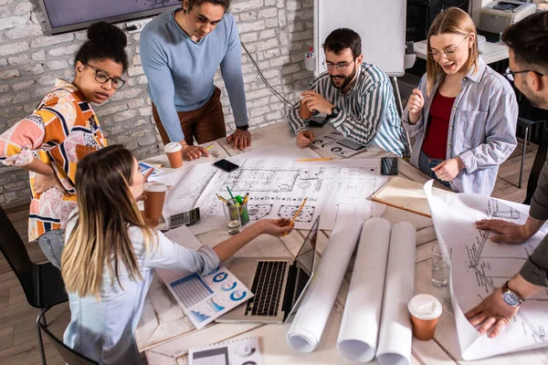 Modern iş adamlarından oluşan bir grup, yaratıcı ofiste mimari tasarımları tartışıyor..