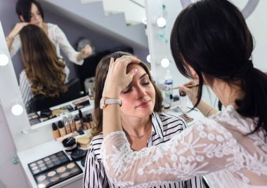 Makyaj sanatçısı güzellik salonundaki modele makyaj yapıyor..