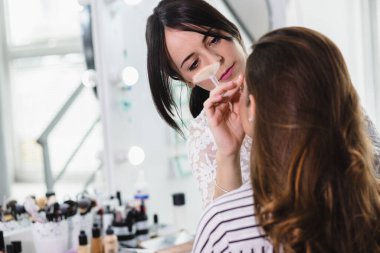 Makyaj sanatçısı güzellik salonundaki modele makyaj yapıyor..