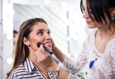 Makyaj sanatçısı güzellik salonundaki modele makyaj yapıyor..