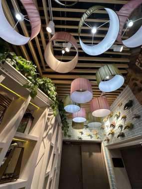 Benzersiz dairesel abajurlar, ahşap tavan yapısı ve dekoratif duvar içeren şık bir iç görünüş.