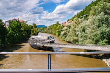 Murinsel, Graz 'da güneşli bir yaz gününde. Graz' daki Murinsel, Mur Nehri üzerinde New York 'lu sanatçı Vito Acconci tarafından 2003 Avrupa' nın Cultur Başkenti olarak tasarlanan ikonik bir yapay yüzme platformudur..