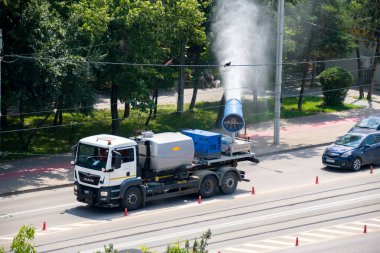 Şehir caddesi, Iasi, Romanya 'da kirlilik önleyici su püskürtme kamyonu. Sis tabancası ya da toz önleyici kamyonlar, PM2.5 ve PM10 gibi havadaki partikül maddeleri azaltmak için ultra ince bir su püskürterek çalışır..