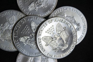 Bir ons Amerikan Kartalı gümüş sikkesi yığını, seçici odak noktası. Amerikan Gümüş Kartalı, Birleşik Devletler 'in ağırlığı ve ağırlığı için ABD hükümeti tarafından garanti edilen 1 ons gümüş külçe sikkesidir. 9 saflık.