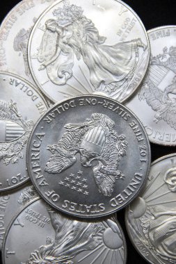 Bir ons Amerikan Kartalı gümüş sikkesi yığını, seçici odak noktası. Amerikan Gümüş Kartalı, Birleşik Devletler 'in ağırlığı ve ağırlığı için ABD hükümeti tarafından garanti edilen 1 ons gümüş külçe sikkesidir. 9 saflık.