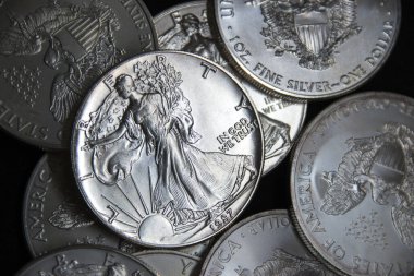 Bir ons Amerikan Kartalı gümüş sikkesi yığını, seçici odak noktası. Amerikan Gümüş Kartalı, Birleşik Devletler 'in ağırlığı ve ağırlığı için ABD hükümeti tarafından garanti edilen 1 ons gümüş külçe sikkesidir. 9 saflık.