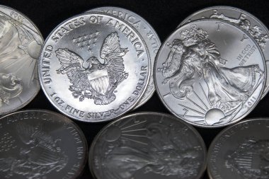 Bir ons Amerikan Kartalı gümüş sikkesi yığını, seçici odak noktası. Amerikan Gümüş Kartalı, Birleşik Devletler 'in ağırlığı ve ağırlığı için ABD hükümeti tarafından garanti edilen 1 ons gümüş külçe sikkesidir. 9 saflık.