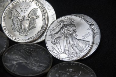 Bir ons Amerikan Kartalı gümüş sikkesi yığını, seçici odak noktası. Amerikan Gümüş Kartalı, Birleşik Devletler 'in ağırlığı ve ağırlığı için ABD hükümeti tarafından garanti edilen 1 ons gümüş külçe sikkesidir. 9 saflık.