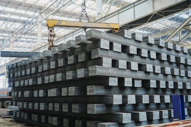 Yüksek sıcaklıkta yuvarlandıktan sonra çelik kirişler düzgünce bir araya toplanır ve soğuk koyu gri metal yüzey endüstriyel oksitlenme rengine sahiptir ki bu da büyük çelik fabrikasının karakteristik özelliğidir.