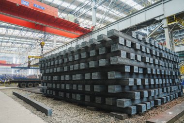 Yüksek sıcaklıkta yuvarlandıktan sonra çelik kirişler düzgünce bir araya toplanır ve soğuk koyu gri metal yüzey endüstriyel oksitlenme rengine sahiptir ki bu da büyük çelik fabrikasının karakteristik özelliğidir.