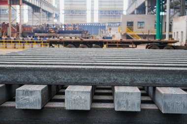 Yüksek sıcaklıkta yuvarlandıktan sonra çelik kirişler düzgünce bir araya toplanır ve soğuk koyu gri metal yüzey endüstriyel oksitlenme rengine sahiptir ki bu da büyük çelik fabrikasının karakteristik özelliğidir.