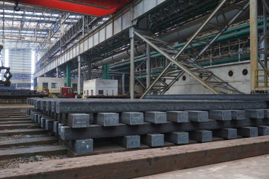 Yüksek sıcaklıkta yuvarlandıktan sonra çelik kirişler düzgünce bir araya toplanır ve soğuk koyu gri metal yüzey endüstriyel oksitlenme rengine sahiptir ki bu da büyük çelik fabrikasının karakteristik özelliğidir.